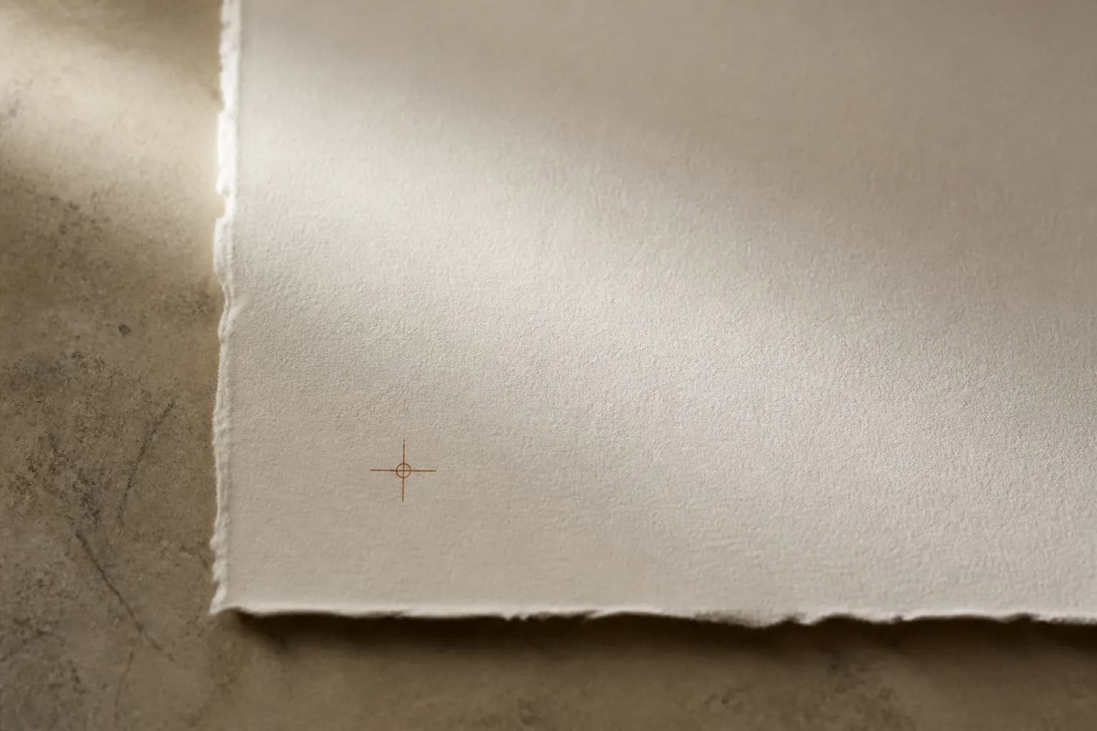 Warm archival paper with a copper registration mark in soft morning light